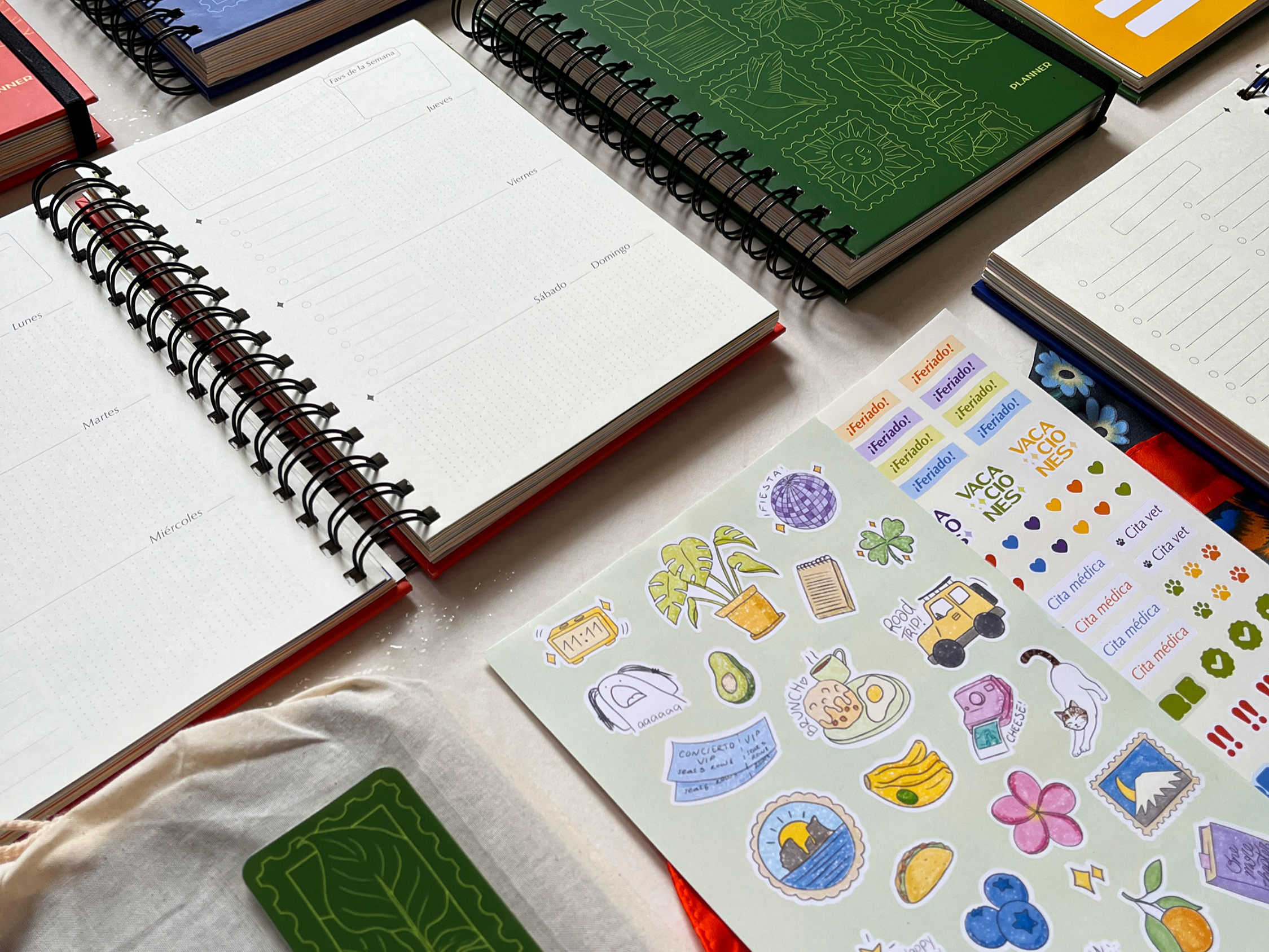 Diversas agendas, cuadernos y papelería colorida y organizadores en una mesa cubierto con tela blanca.