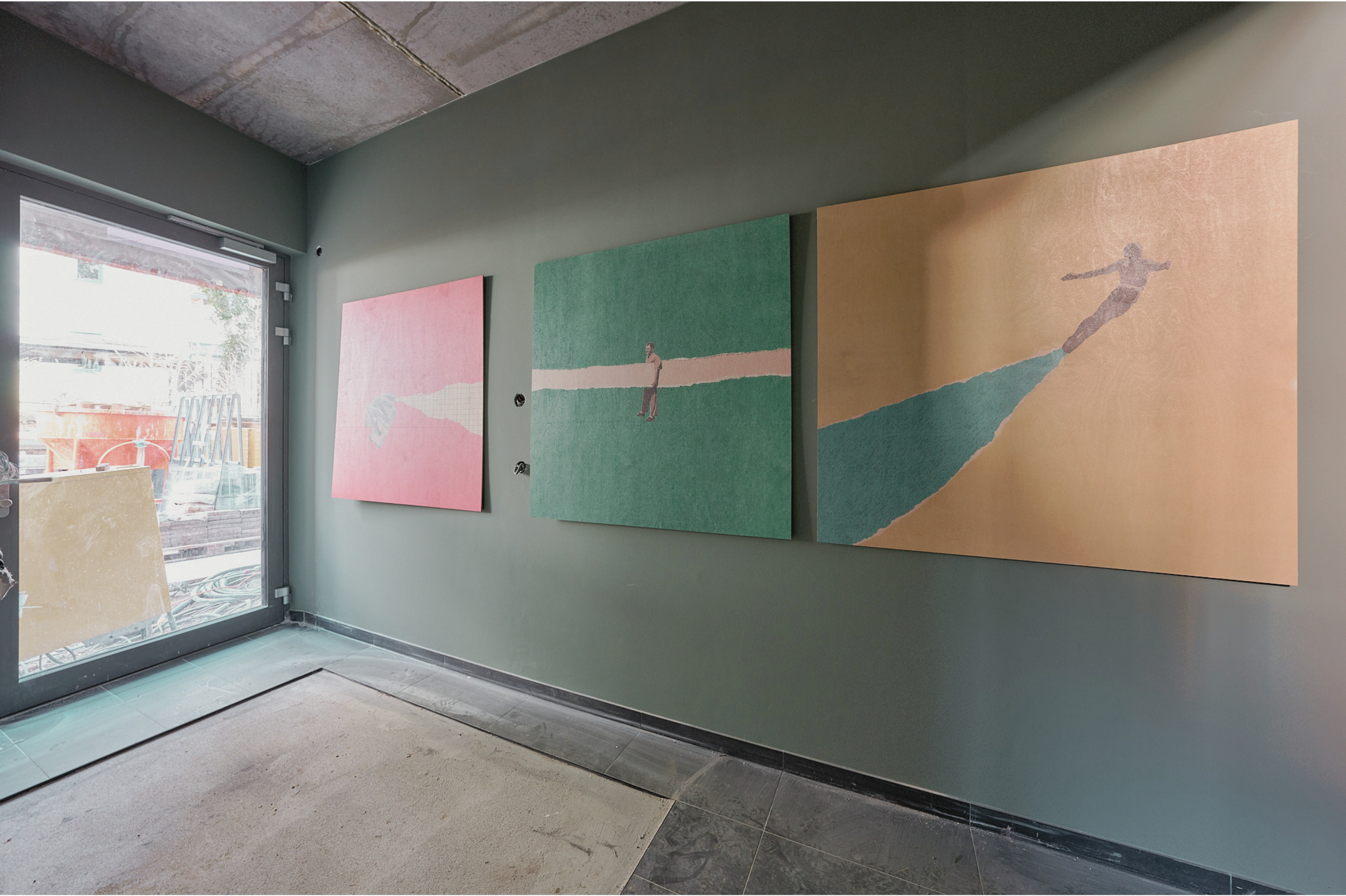Innenaufnahme eines Kunstgalerieraums mit four gemalten Bildern an der Wand, neben einem großen Fenster, das Tageslicht hereinlässt.
