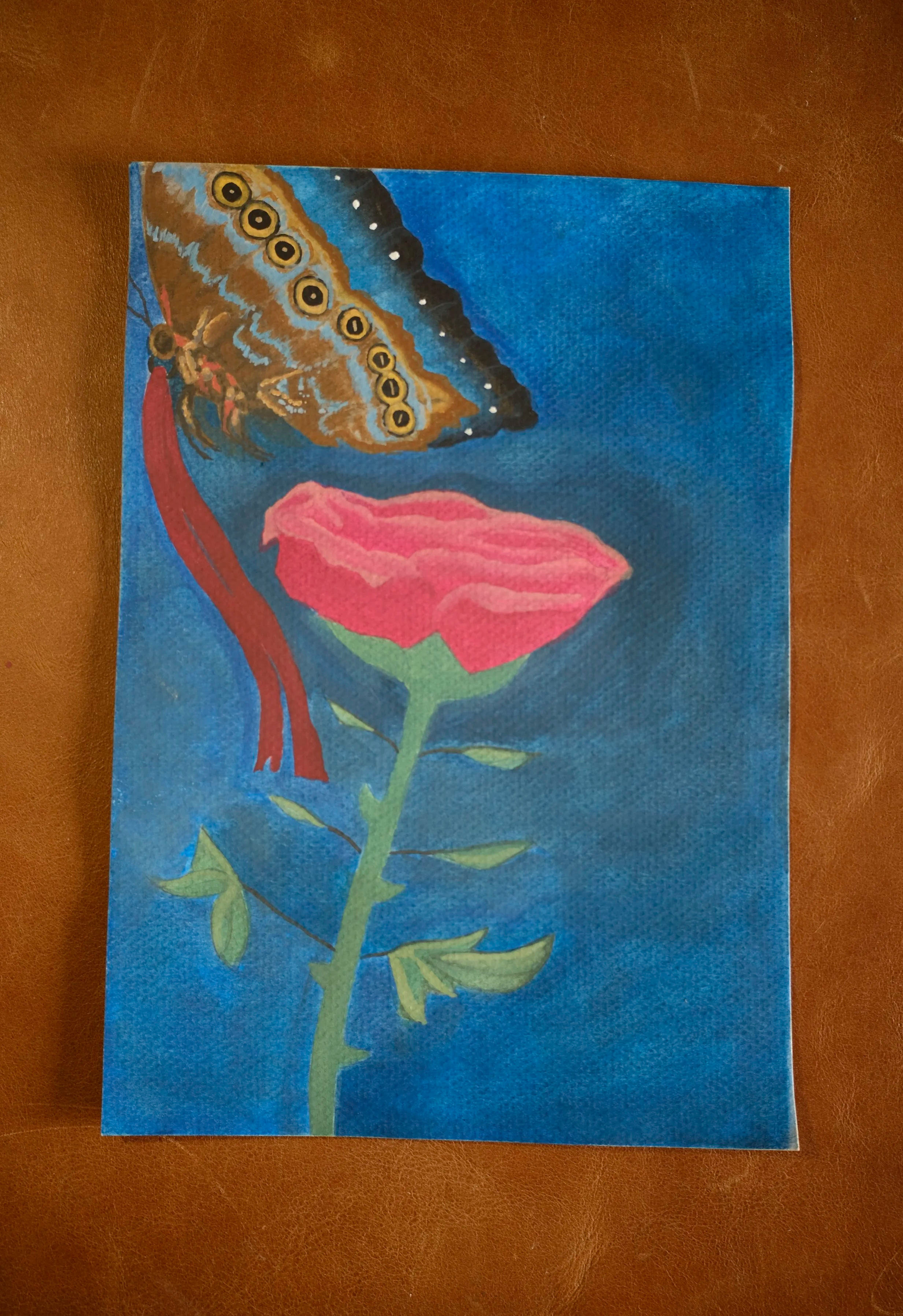 Hand-painted picture of a butterfly on a pink flower, set against a blue background.