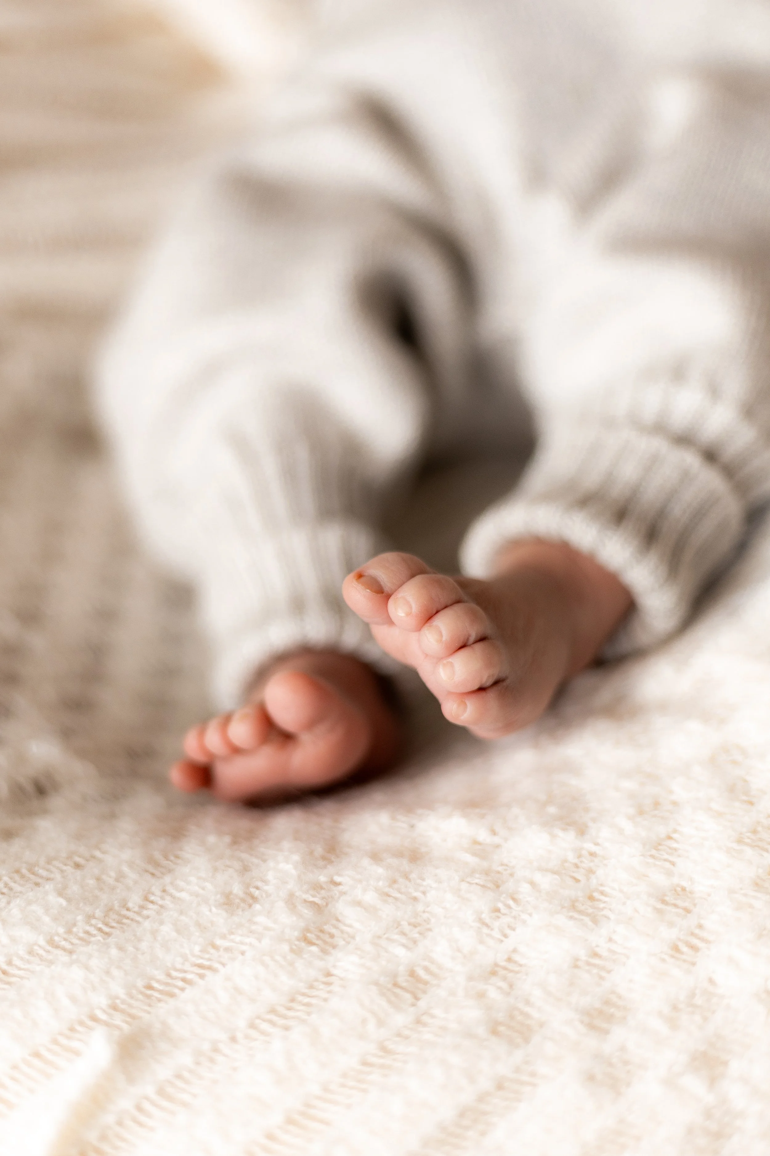 Nahaufnahme eines Babyfusses auf einer weichen, hellbeigen Decke