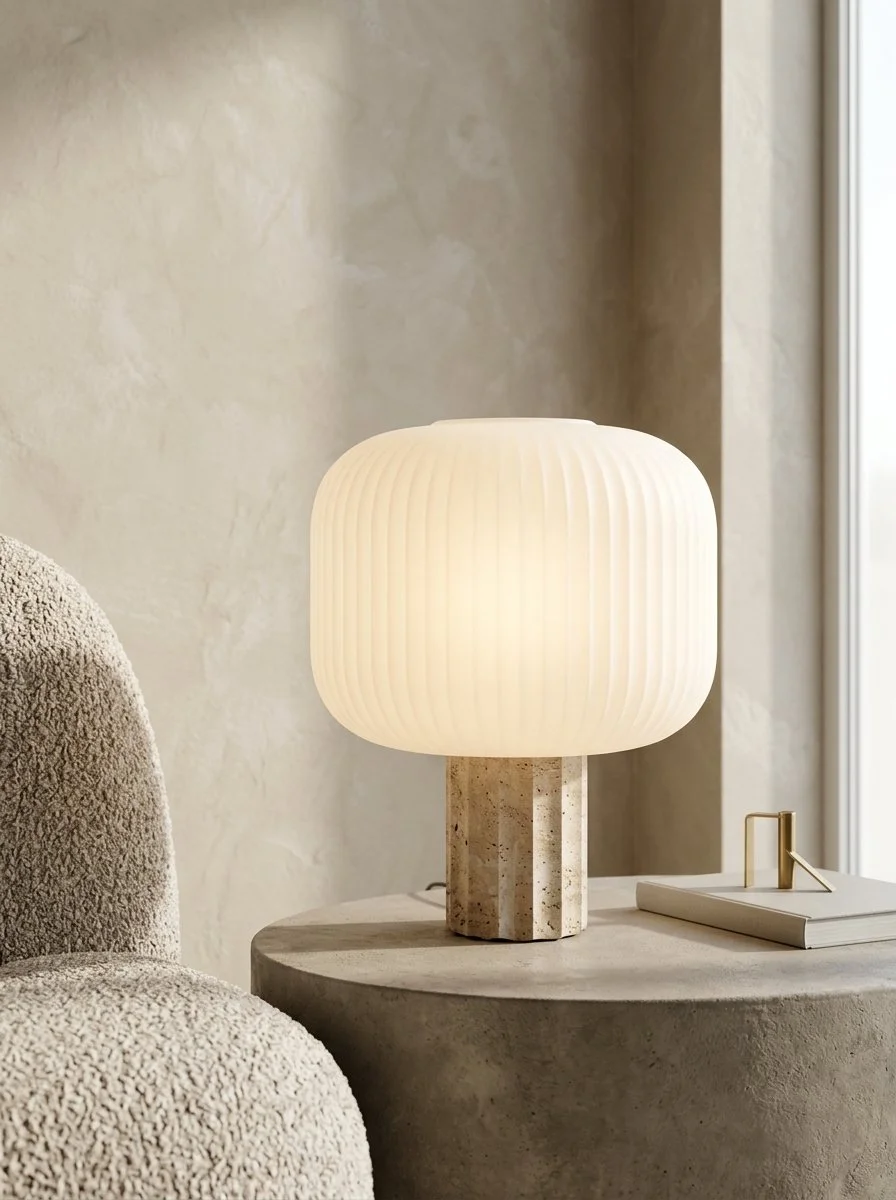 Lampe de table avec abat-jour en verre blanc et support en pierre, sur une table en béton dans un intérieur moderne