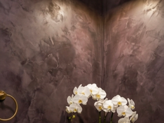 Une plante d'orchidée blanche dans un vase sur une surface, contre un mur en stuc gris