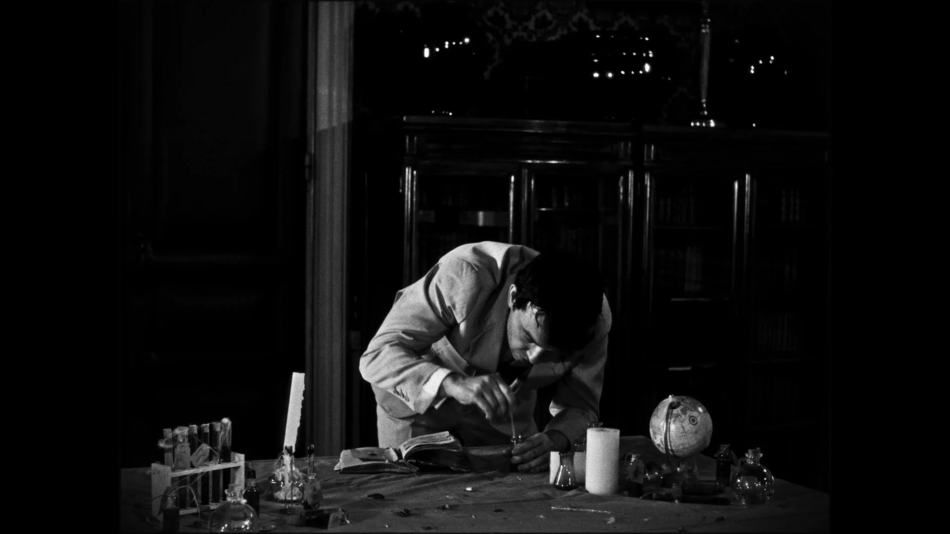 A man is working with scientific equipment on a table in a dimly lit room.