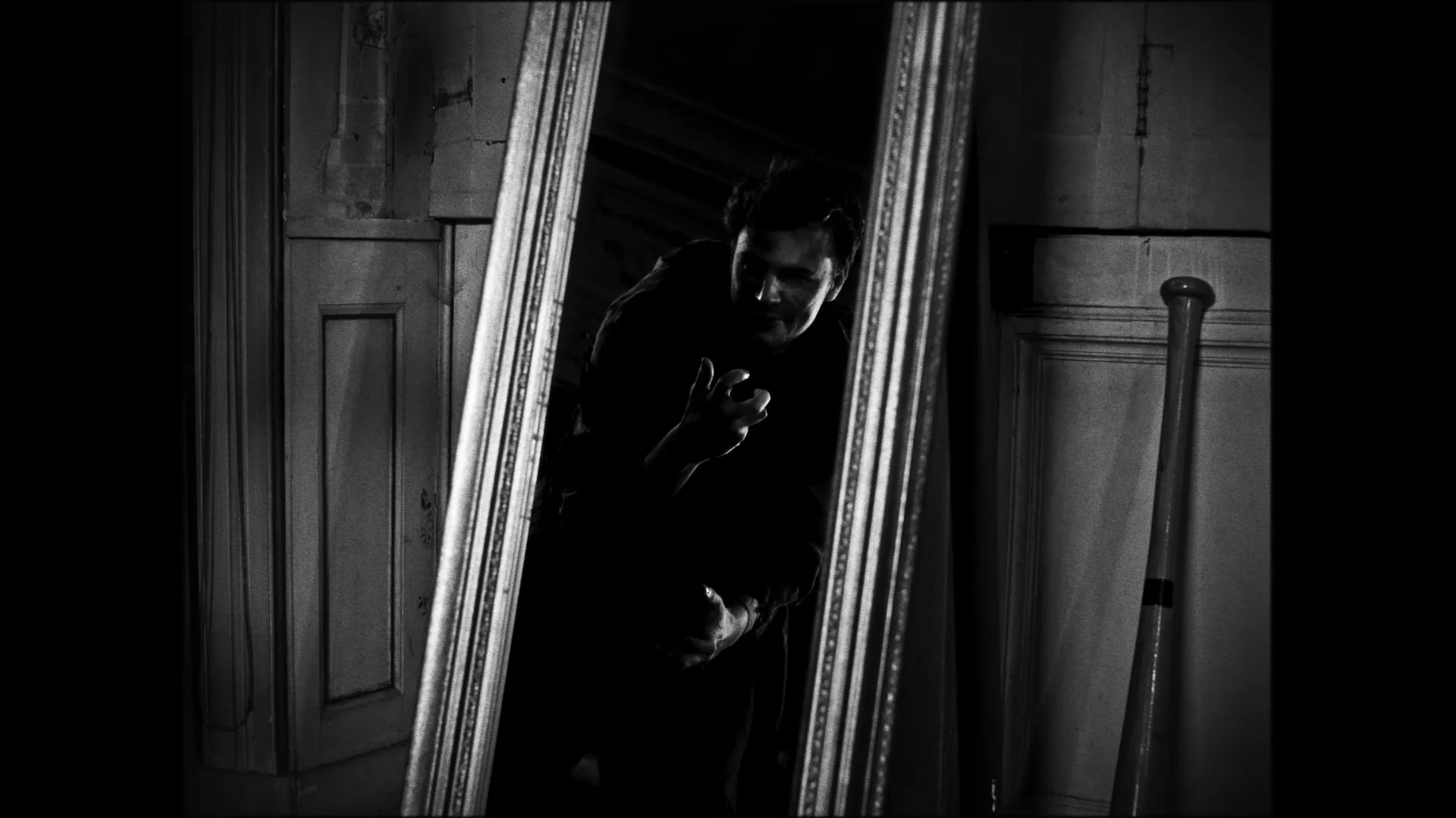 A person looking into a mirror with dramatic lighting, creating a mysterious atmosphere in a vintage room.