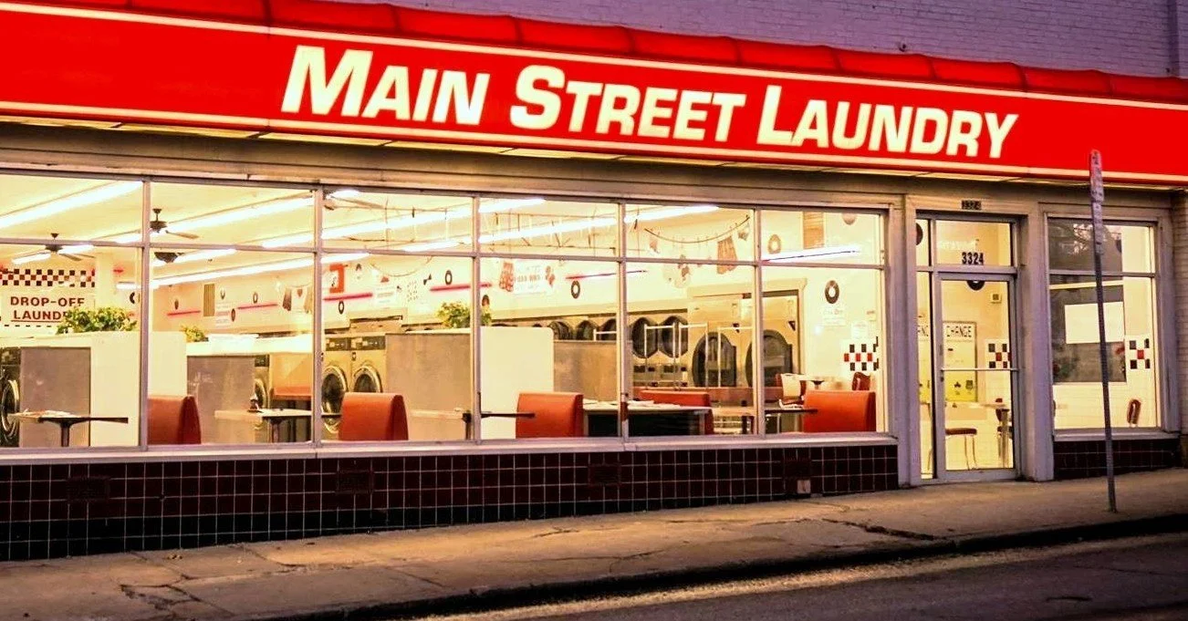 Main Street Laundry laundromat storefront in Kansas City, MO, featuring large-capacity washers and dryers visible through the front windows.
