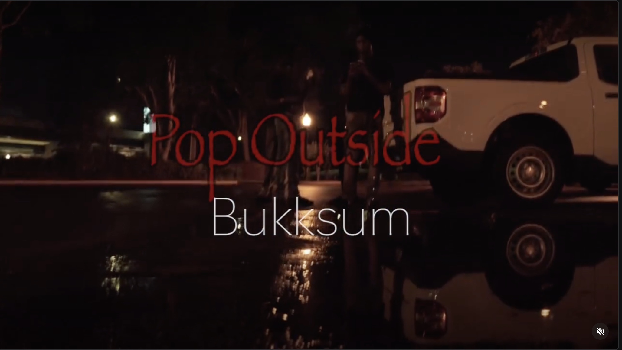 Nighttime scene with two people standing near a white truck, reflected on wet pavement, with the word "PopOutside" in red text and "Buksum" in white text overlayed on the image.