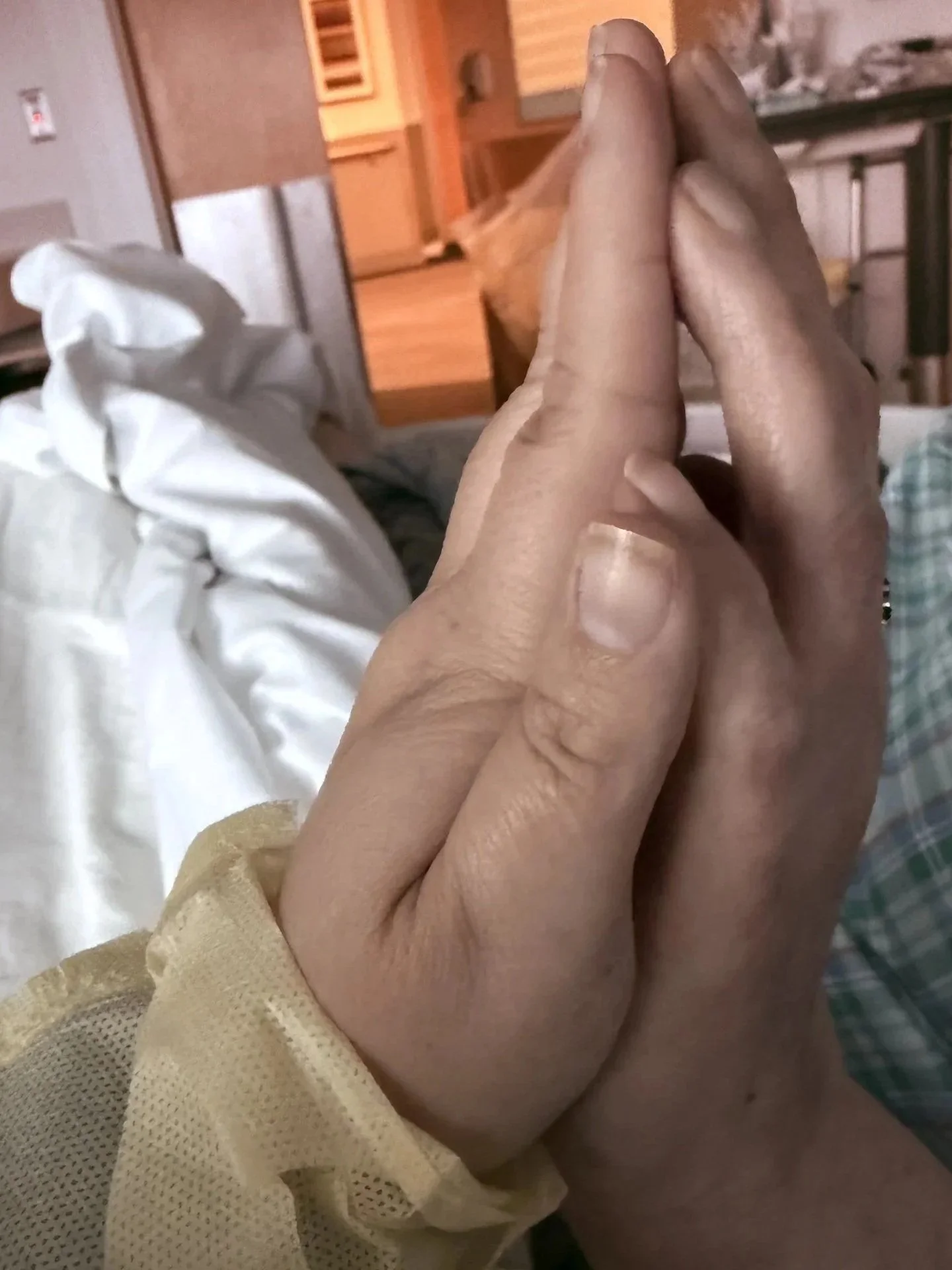 A person holding hands with another person in a hospital or care setting.