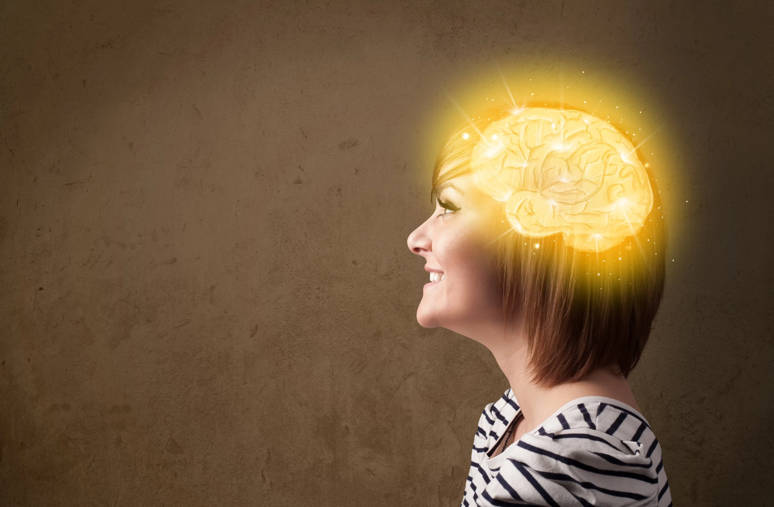 Side profile of a smiling young girl with brown hair in a striped shirt, with a glowing, stylized brain illustration over her head, indicating thinking or creativity.