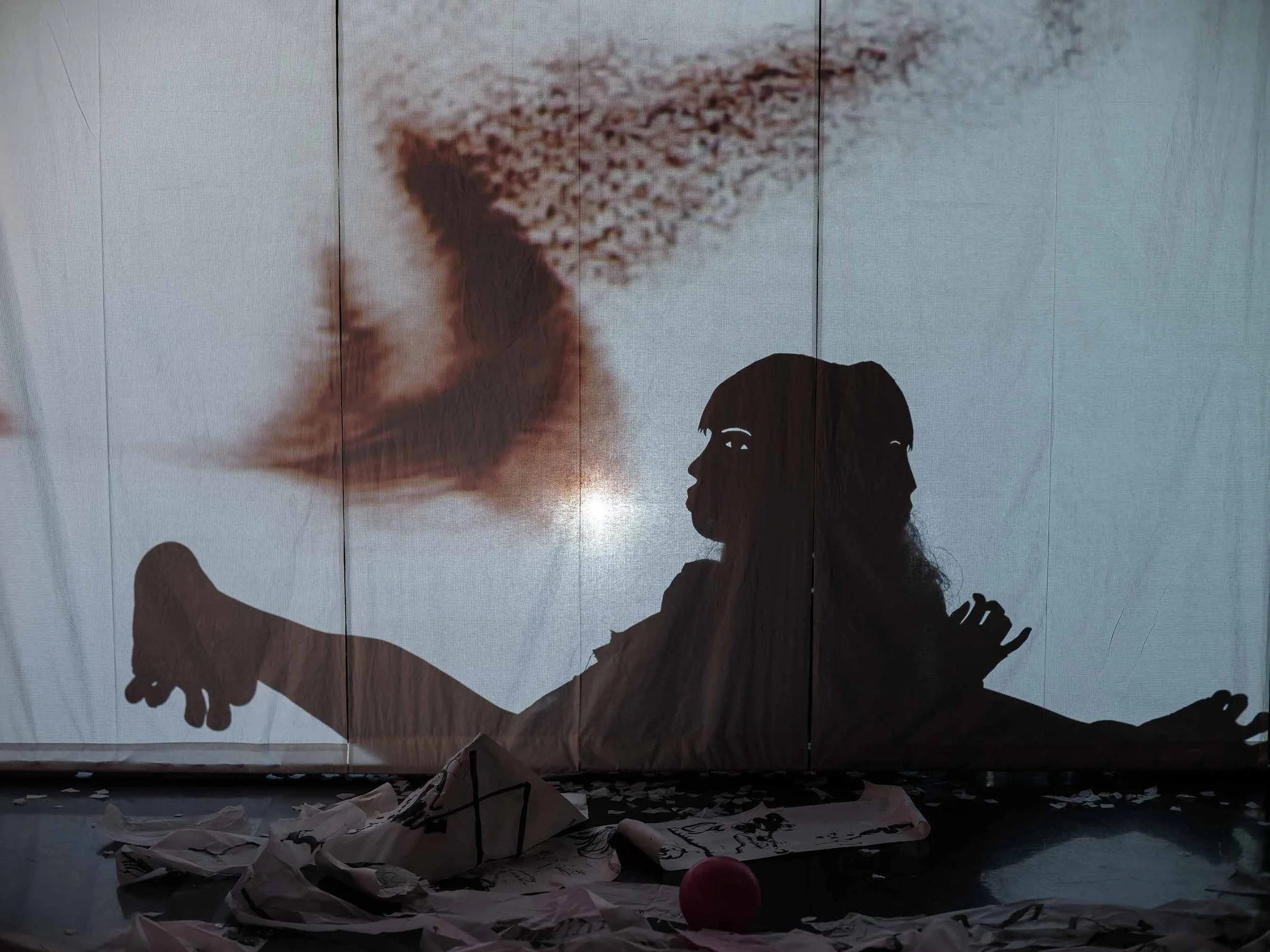 A figure wearing a shadow puppet mask contorting their body. 