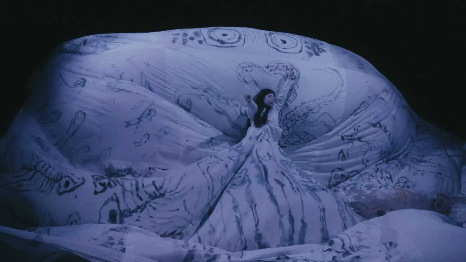 A still from the short film Stone Skin. A woman in a fabric ocean painted by Rachel Gray.
