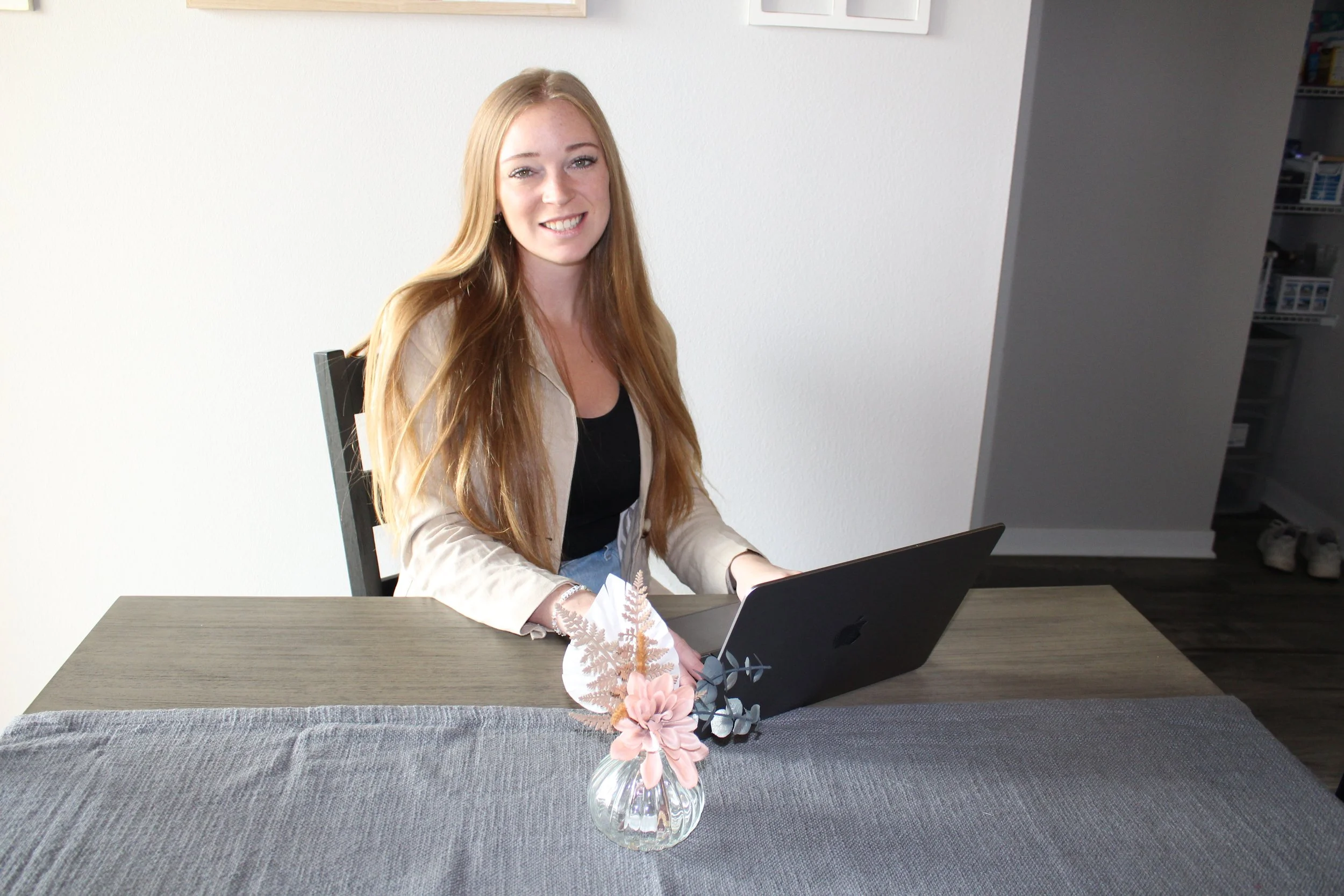 A woman with a laptop, completing nutrition coaching calls and blogs.