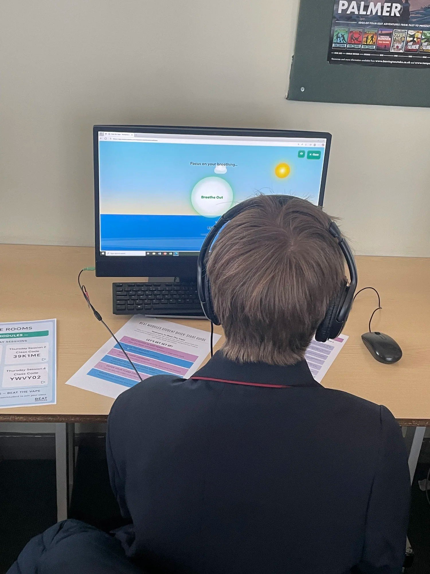 A pupil wearing headphones using Beat Modules on a computer