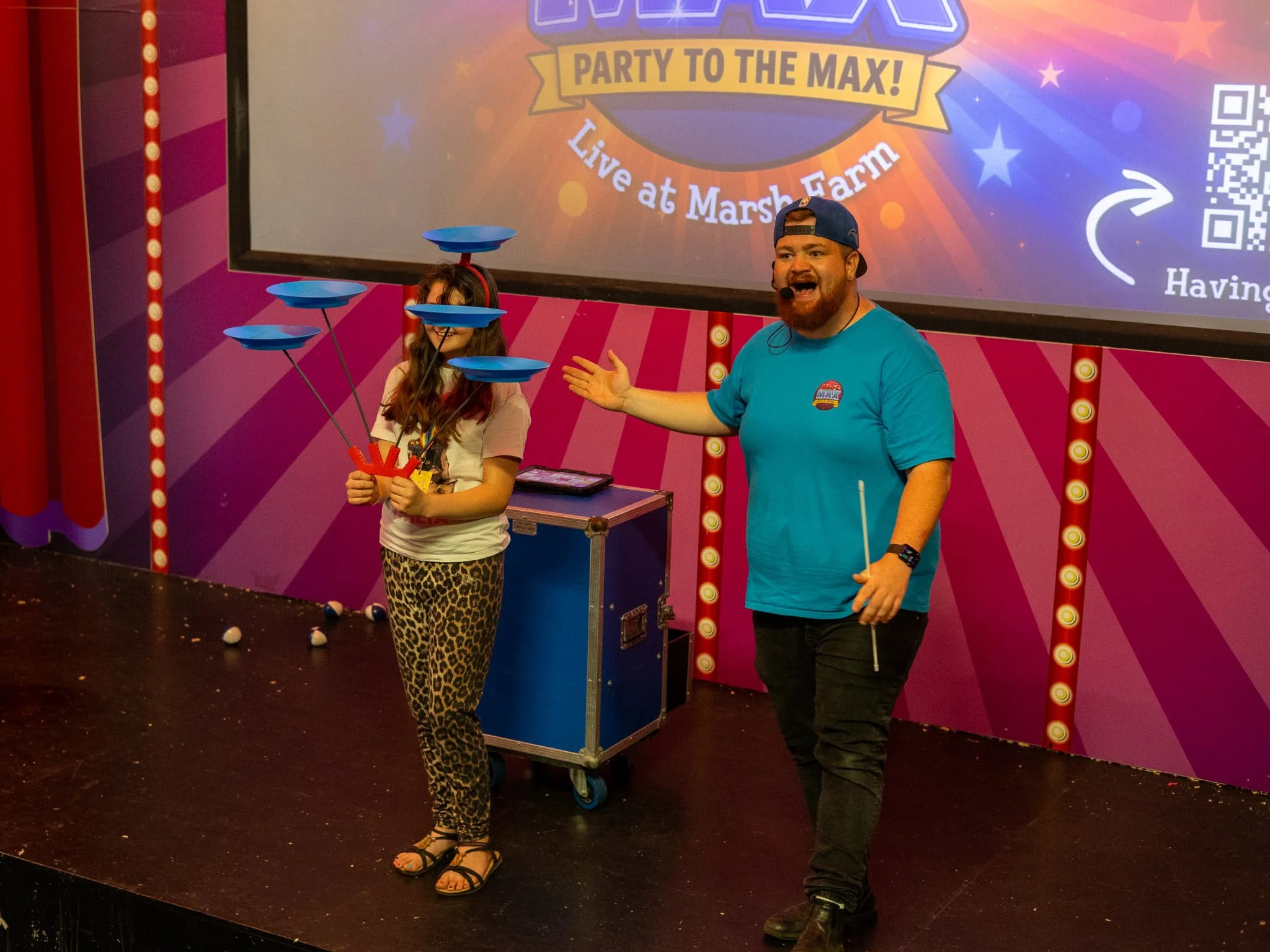Magic Max and a child spinning plates on a stage