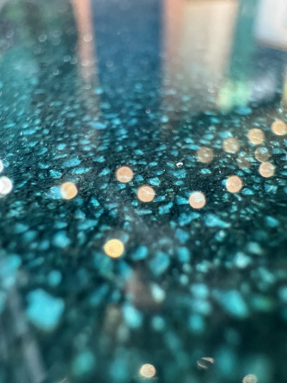 Close-up of a shimmering, textured turquoise epoxy floor with small reflective specks