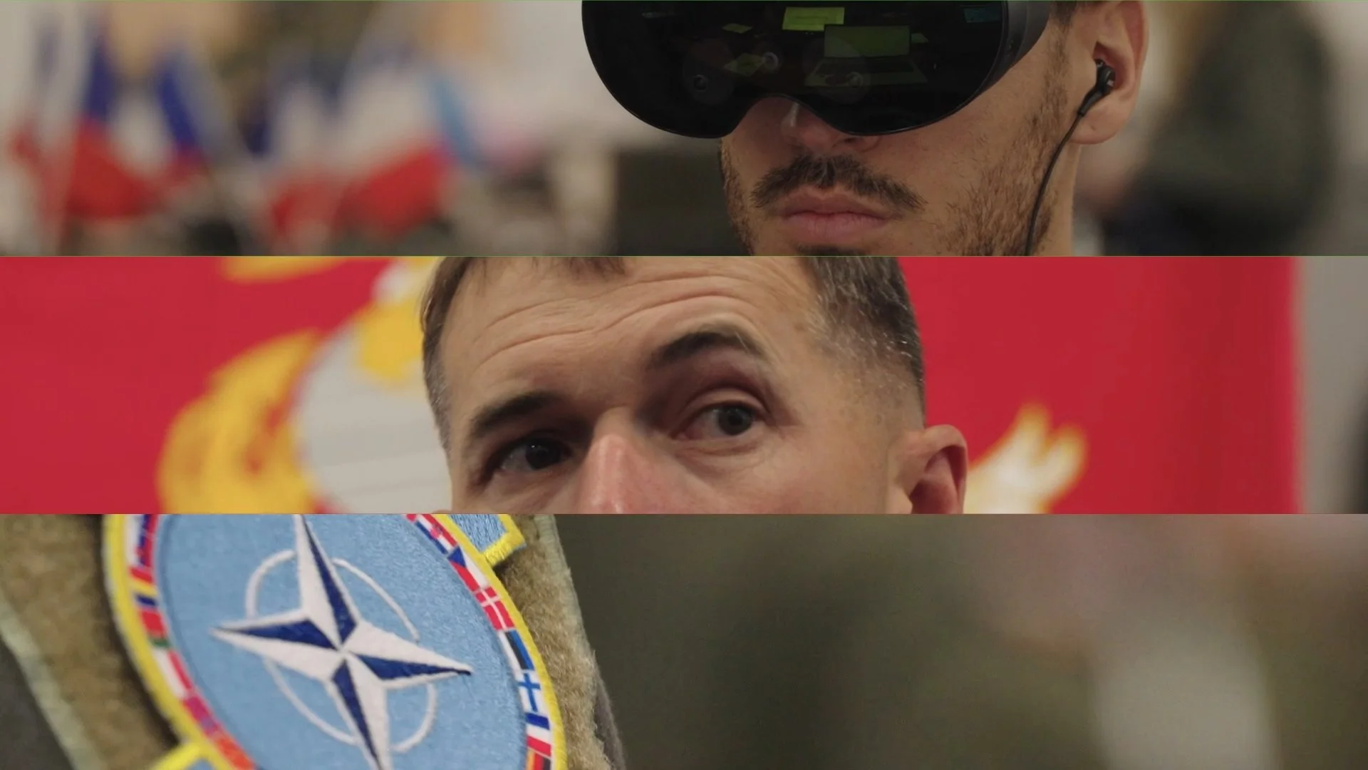 Close-up view of two men's faces, with one wearing a virtual reality headset and earphones, and the other in front of a red background with a NATO emblem patch visible on their clothing.