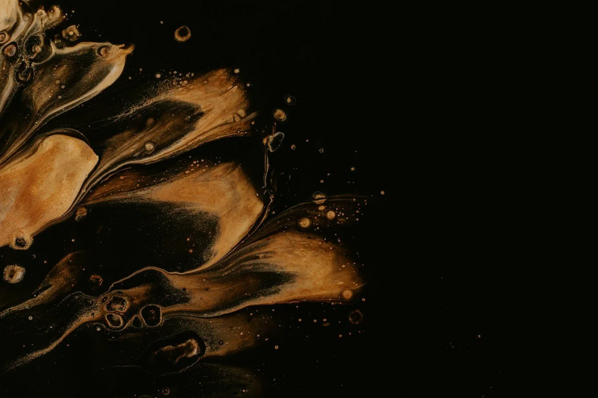 Abstract composition of gold and black swirling liquids and bubbles.