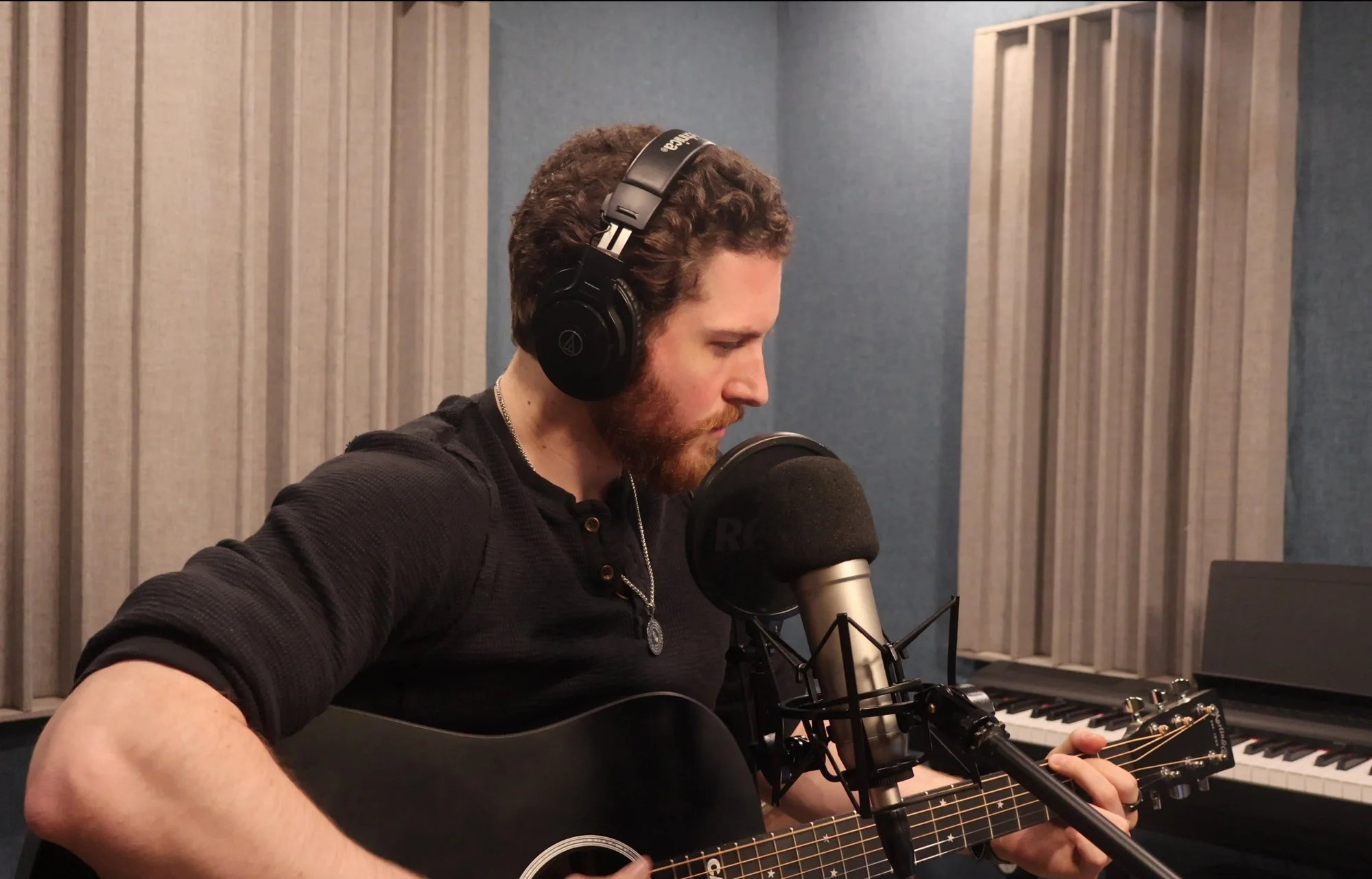 John Matthew Gillen singing and playing acoustic guitar in a recording studio