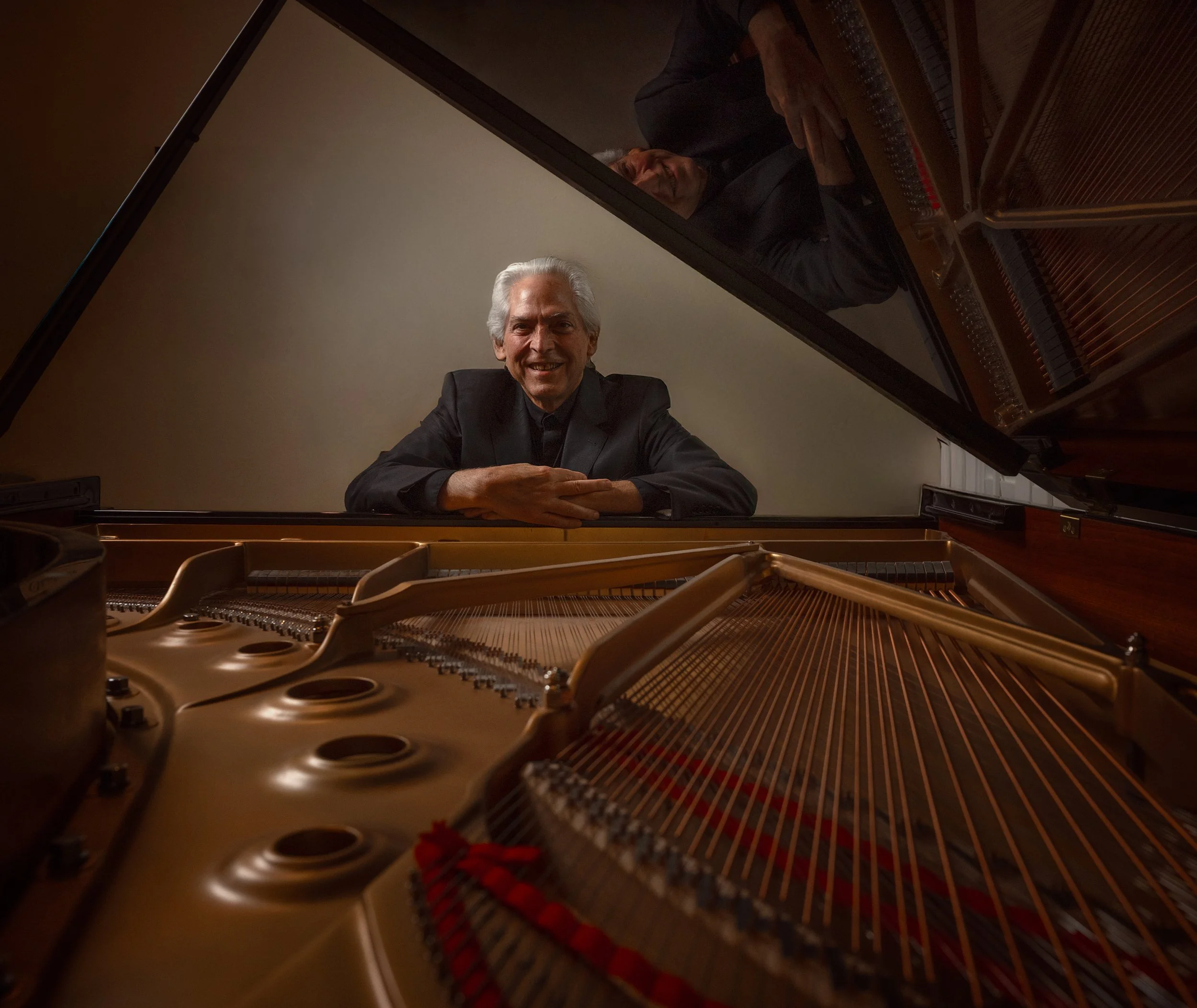 David Masterson, piano teacher in Pinehurst, NC is seen in the lid of an open grand piano, with strings and hammers in the foreground