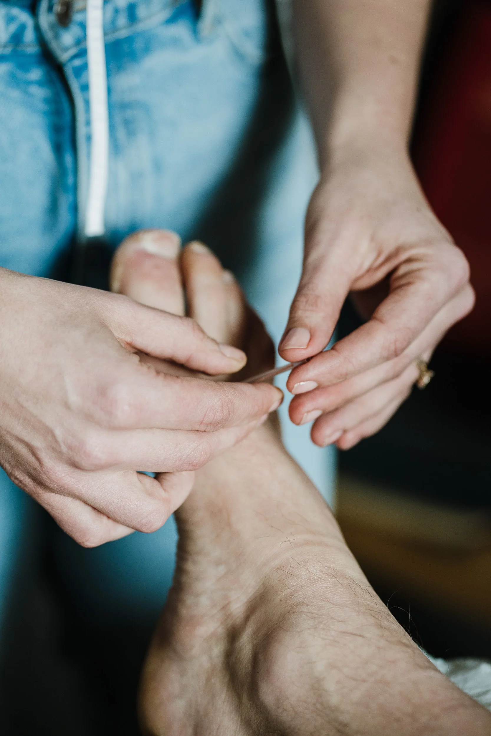 Two people holding hands, one older and one younger, with a focus on their hands and wrists.