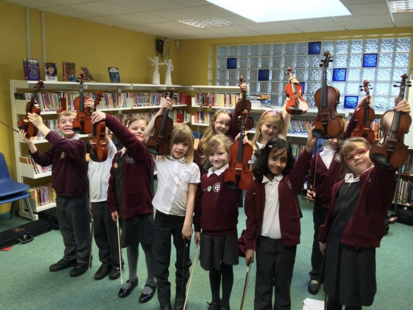 Year 2 pupils holding up their violins