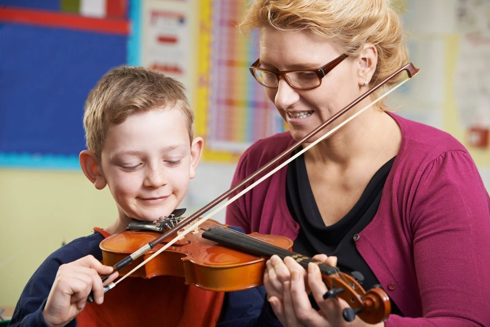 A music teacher helping a pupil with the violin