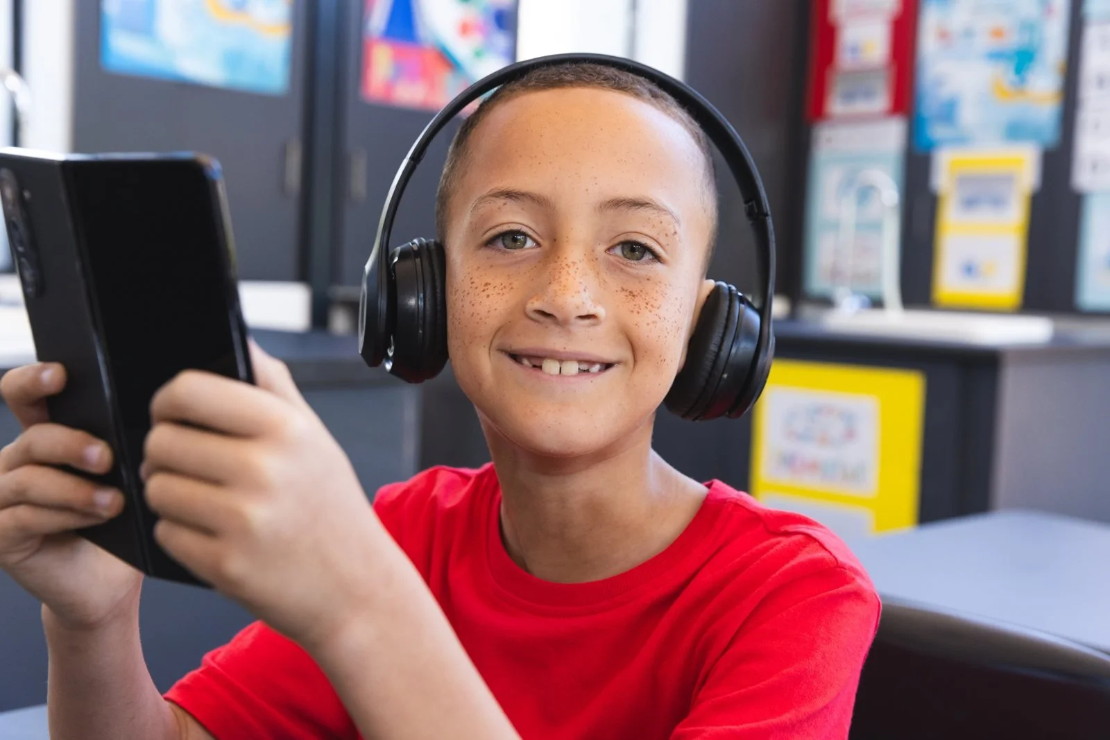 A pupil with headphones using a tablet in class