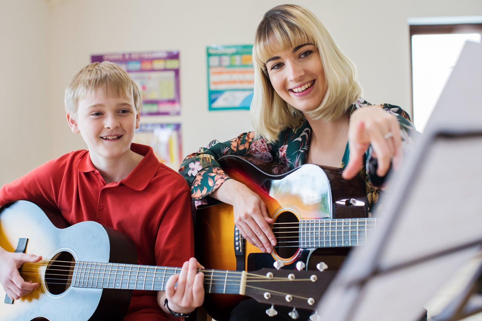 A music teacher and pupil playing guitar together