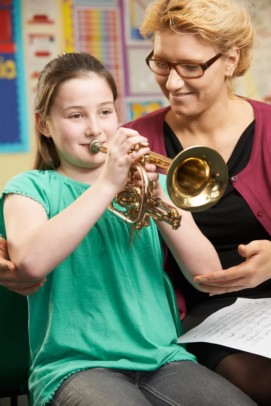 A music teacher supporting a pupil playing the cornet