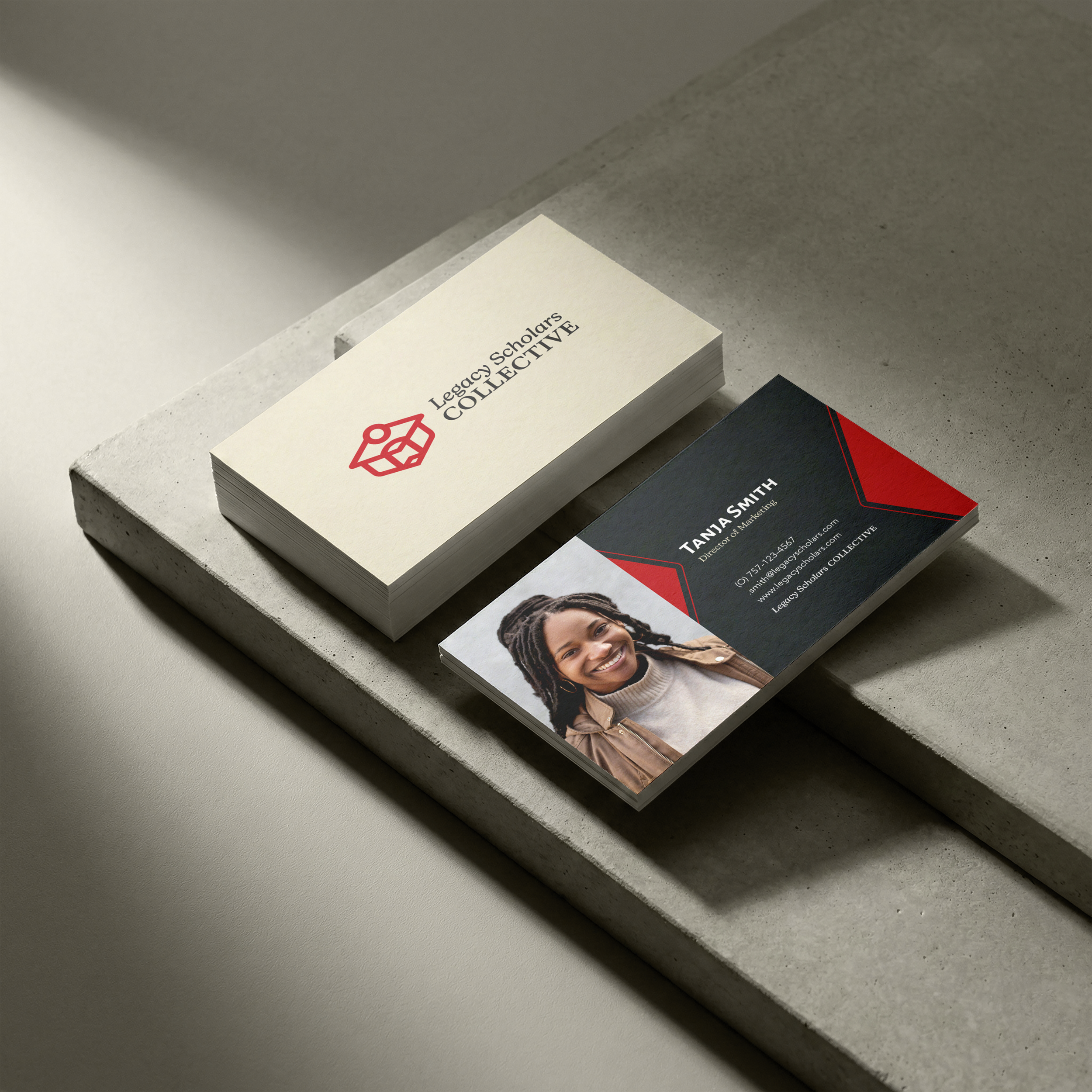 Stack of business cards on concrete surface, with a focus on one card reading 'Legacy Scholars COLLECTIVE' and containing contact information, along with a blurred image of a smiling woman.