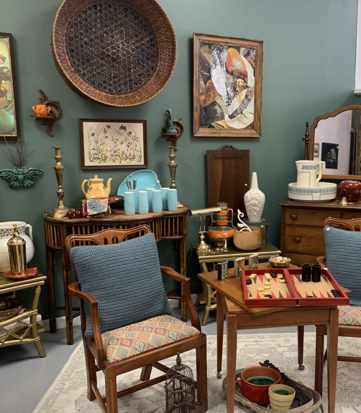 A cozy antique-filled room with chairs, tables, and assorted decorative items on the walls and surfaces.