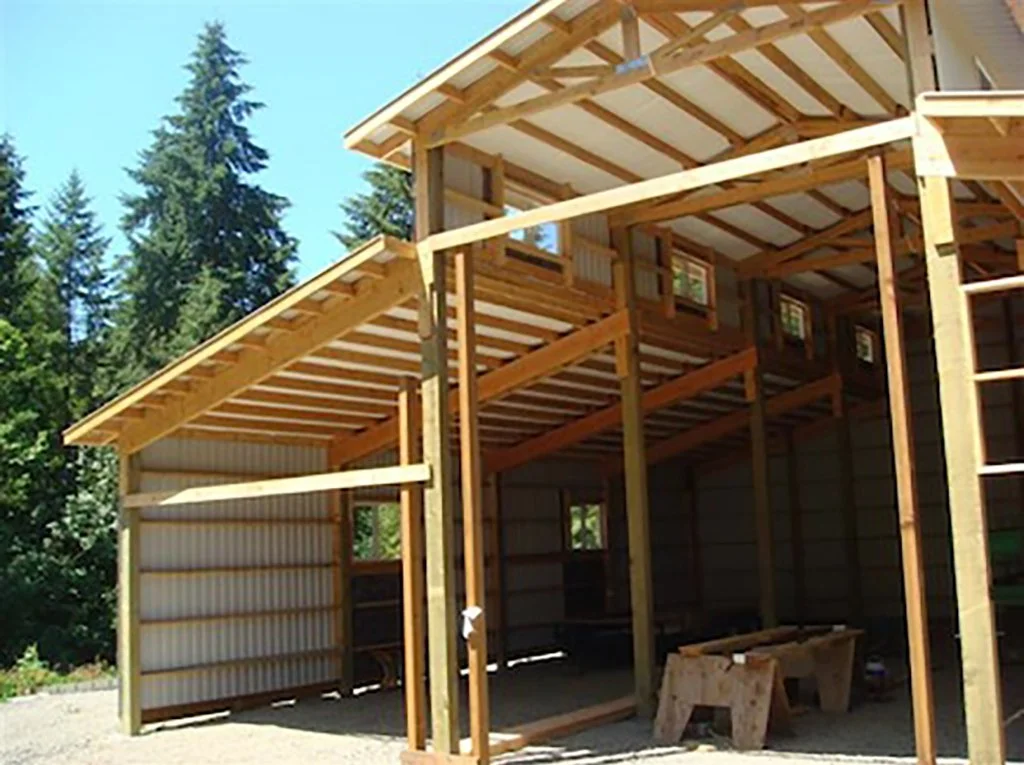 Under construction wooden house framework with trees in the background.