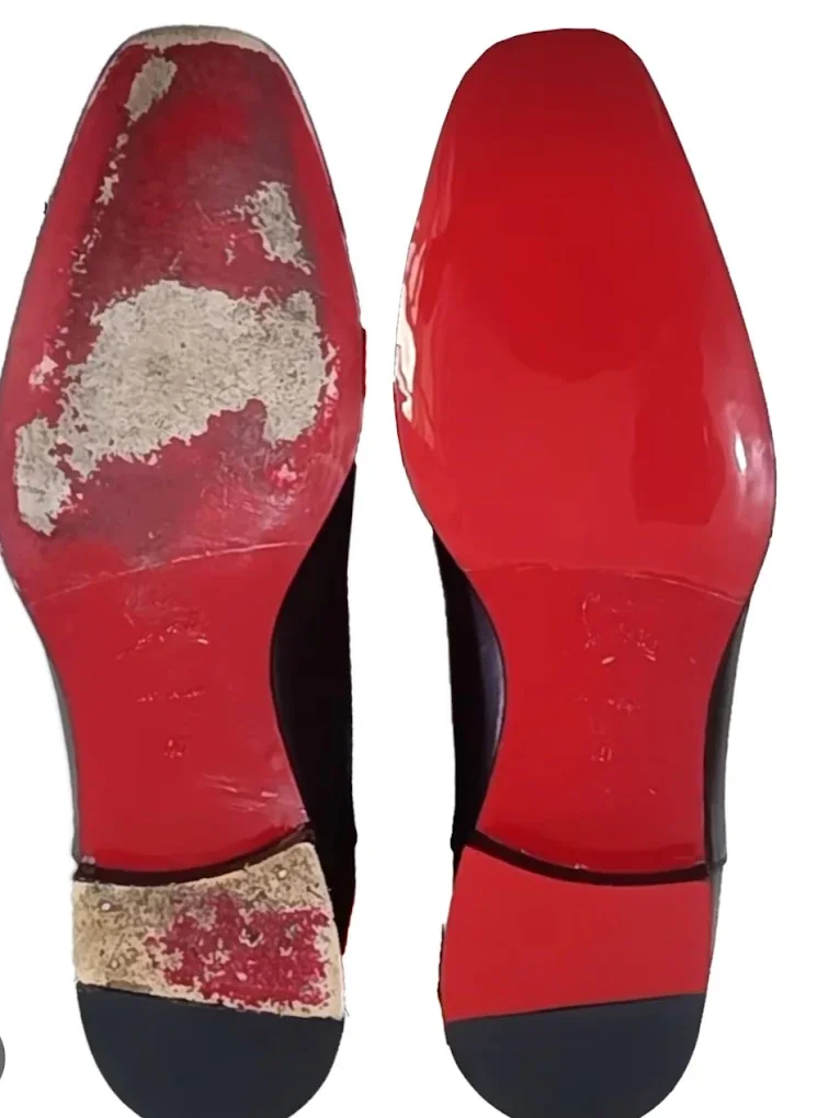 Pair of worn-out red and black shoes, with the soles showing significant dirt and damage.