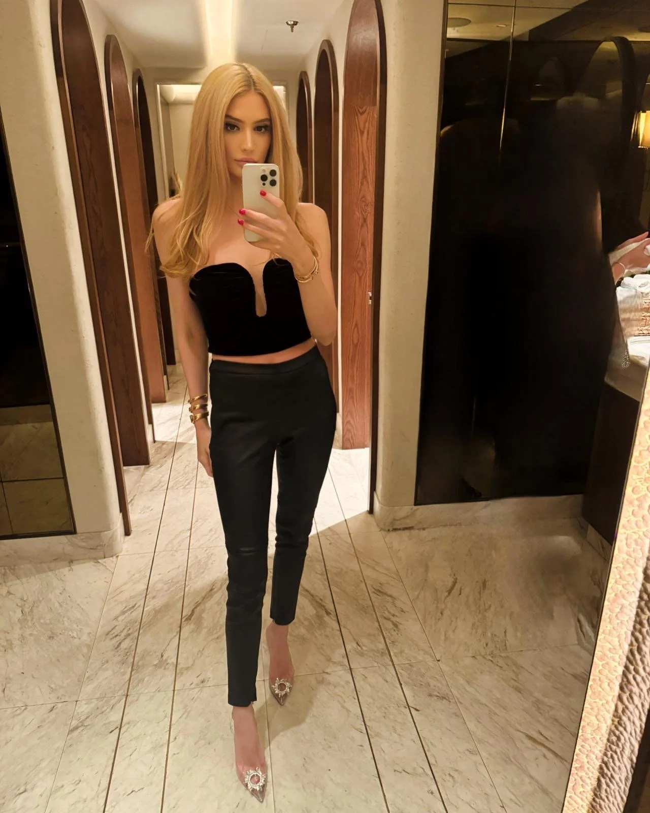 Sienna Blakely, a high-class independent escort in London, wearing an elegant black strapless top, tailored trousers and sparkling heels for a sophisticated evening out.