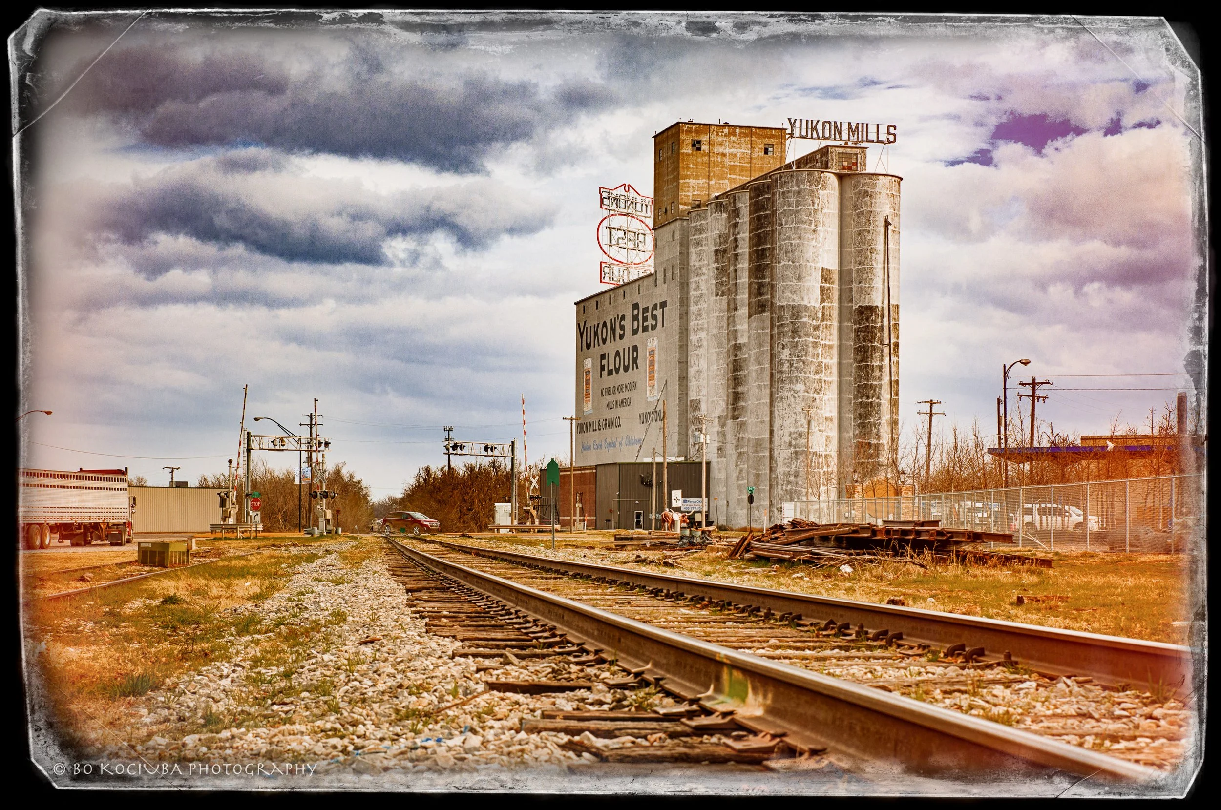 Historic Yukon Mills grain elevator beside railroad tracks in Yukon, Oklahoma, showing the town's longstanding connection to agriculture and rail transportation.