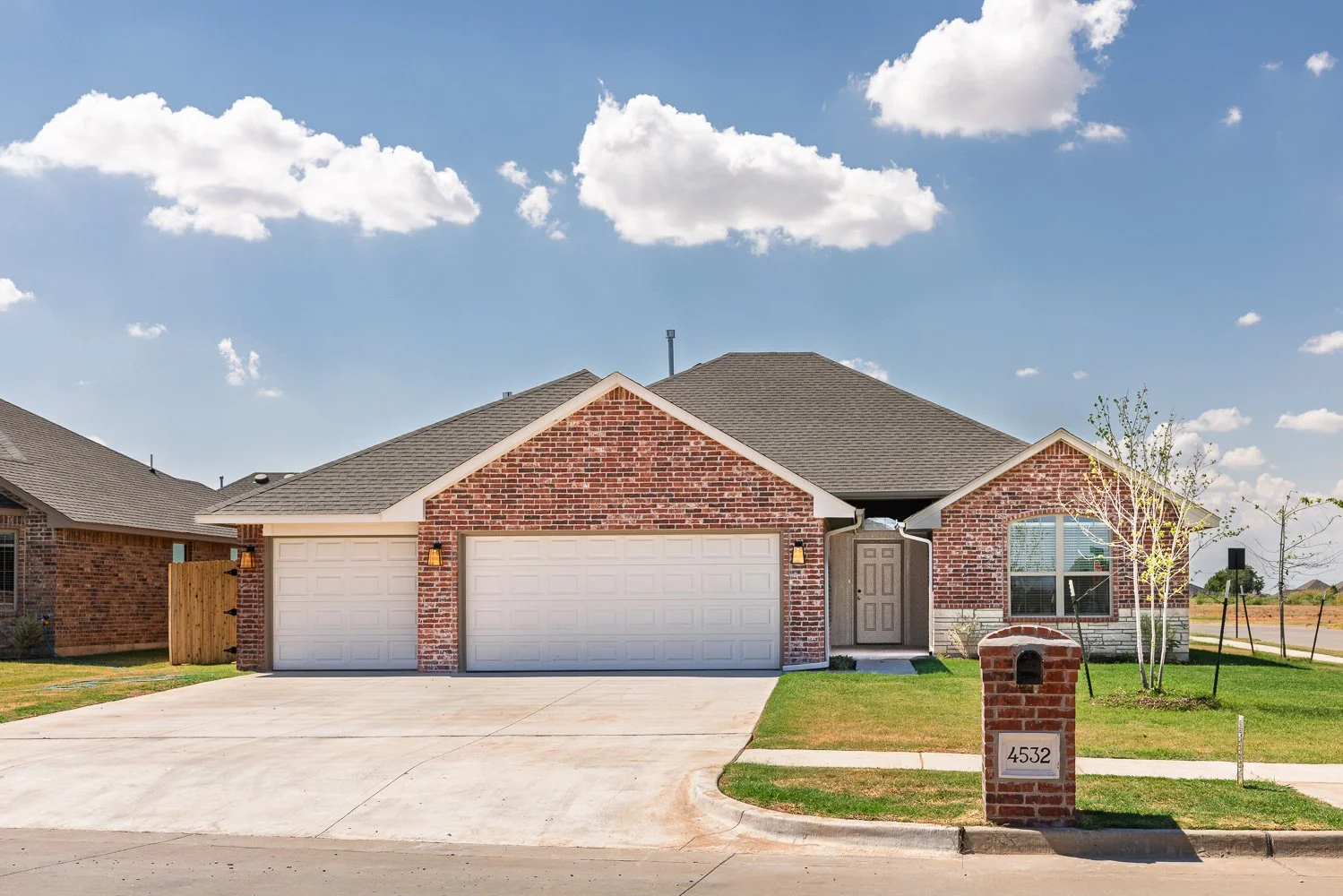 Single-story brick home with an attached two-car garage, concrete driveway, and landscaped front yard.