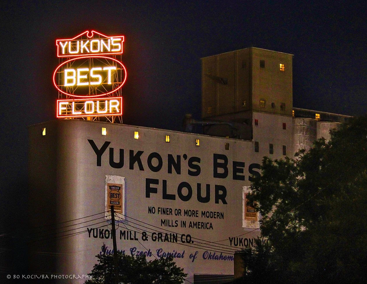Historic Yukon Flour Mill in Yukon, Oklahoma, illuminated at night with its recognizable neon Yukon's Best Flour sign.