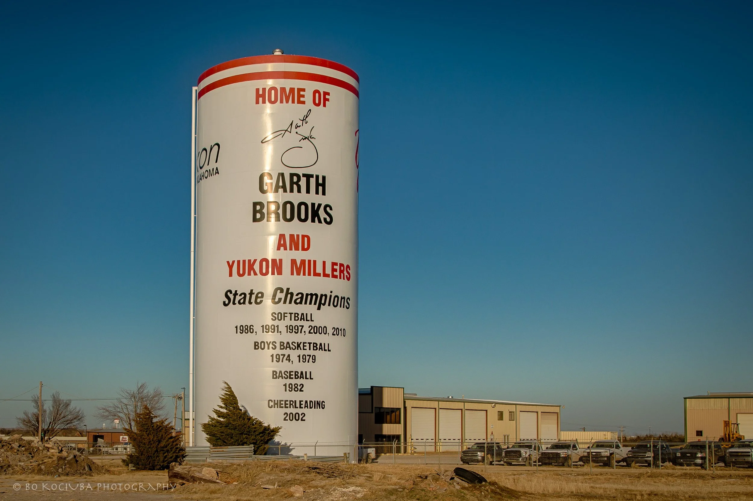 Yukon water tower in Yukon, Oklahoma, displaying the Yukon Millers' athletic championship achievements against a clear blue sky.