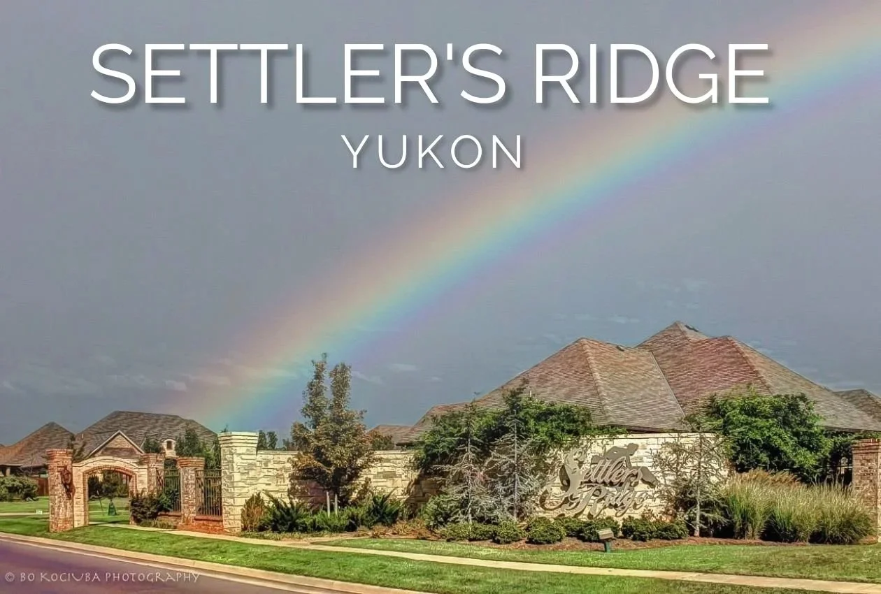 Settlers Ridge neighborhood in Yukon, Oklahoma, with brick homes, landscaped entrance, and a rainbow stretching across the sky.