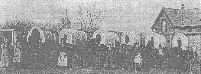 Historic black-and-white group photograph in Mustang, Oklahoma, showing people gathered outside a building beside large decorative letters.