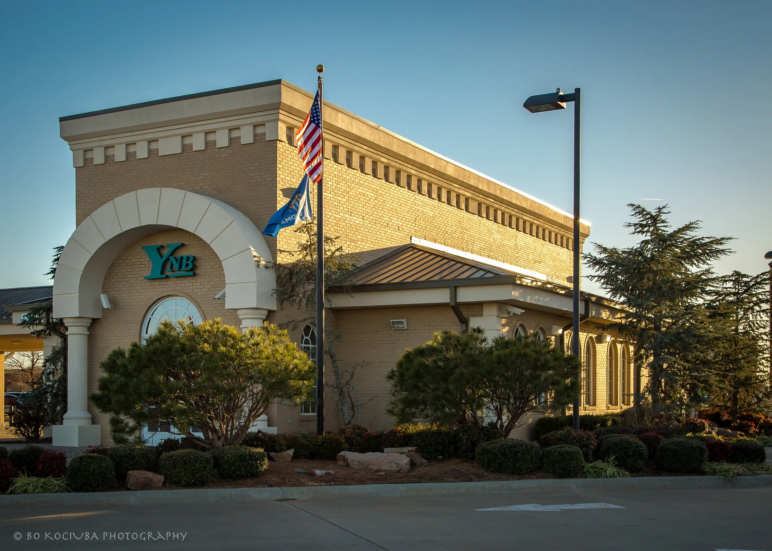 Yukon National Bank building in Yukon, Oklahoma, featuring a brick facade, arched entrance, and American and Oklahoma flags outside.