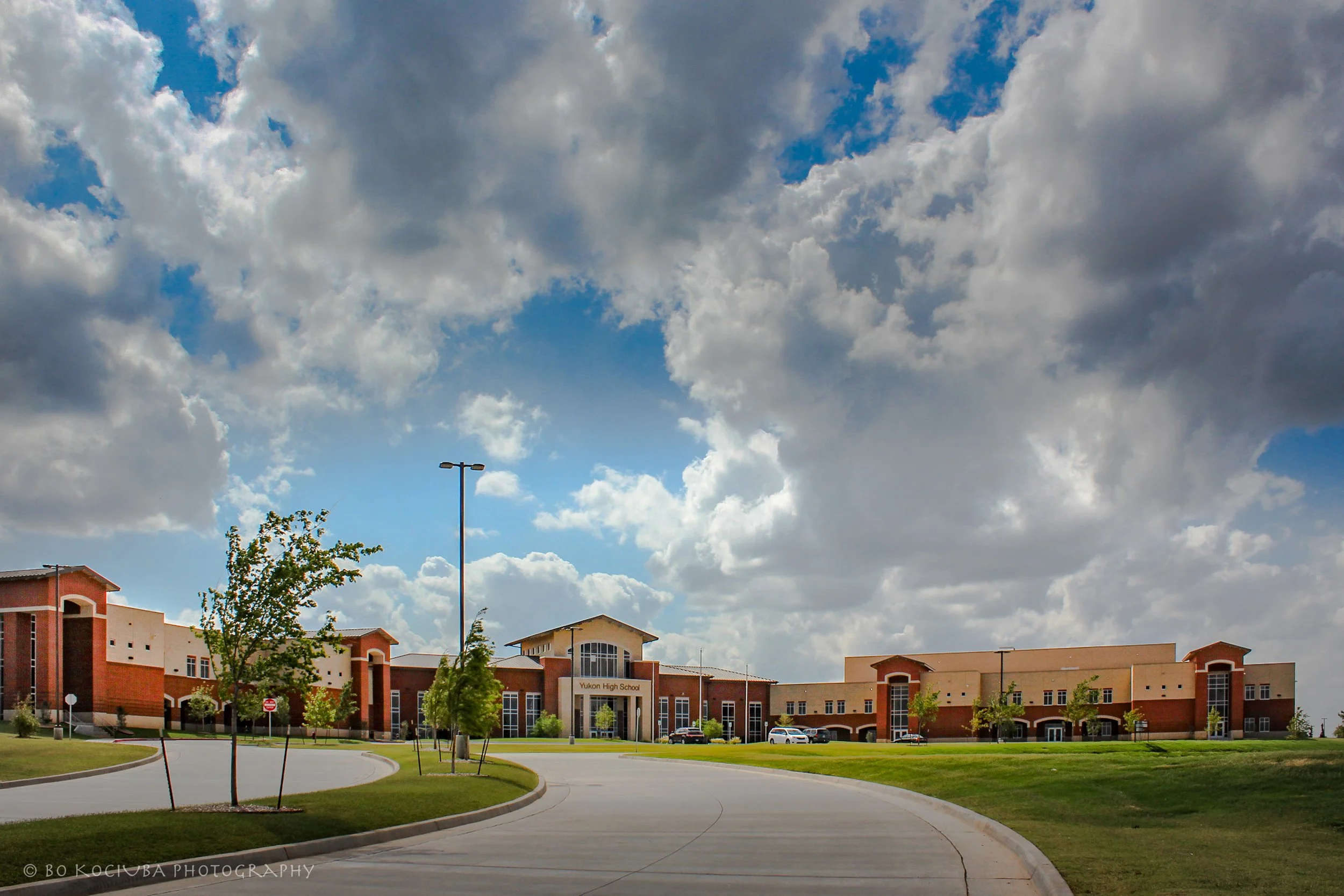Yukon High School campus in Yukon, Oklahoma, featuring the new school building, landscaped grounds, curved entrance drive, and parking area.