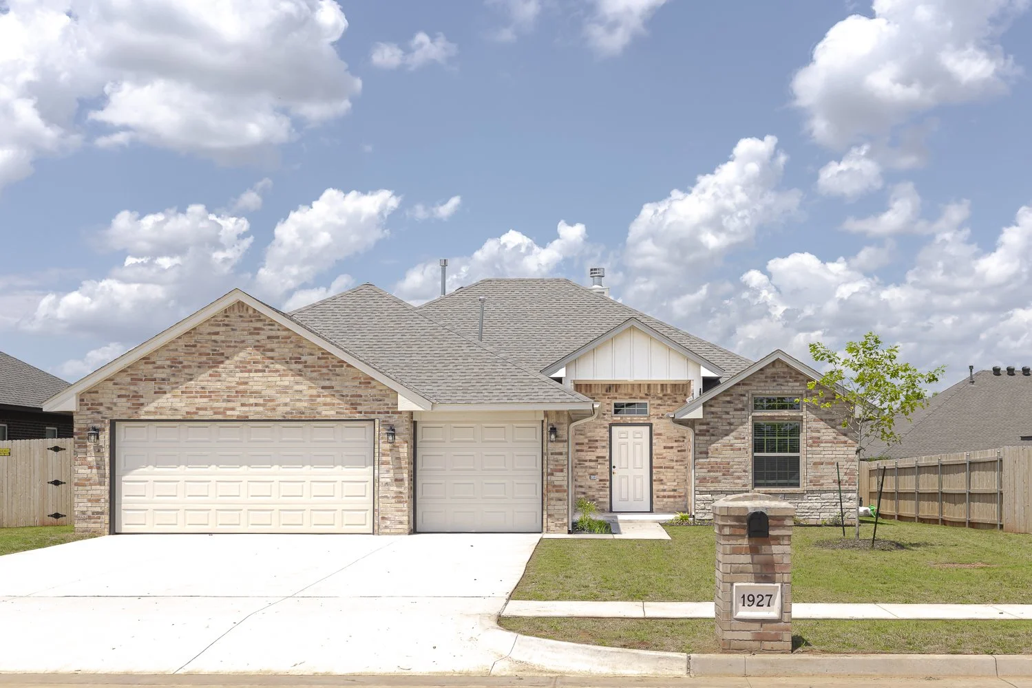 Brick and siding home at 1927 W Flintlock Way in Hunters Hill, Mustang, Oklahoma, featuring an attached garage, landscaped front yard, and brick mailbox.