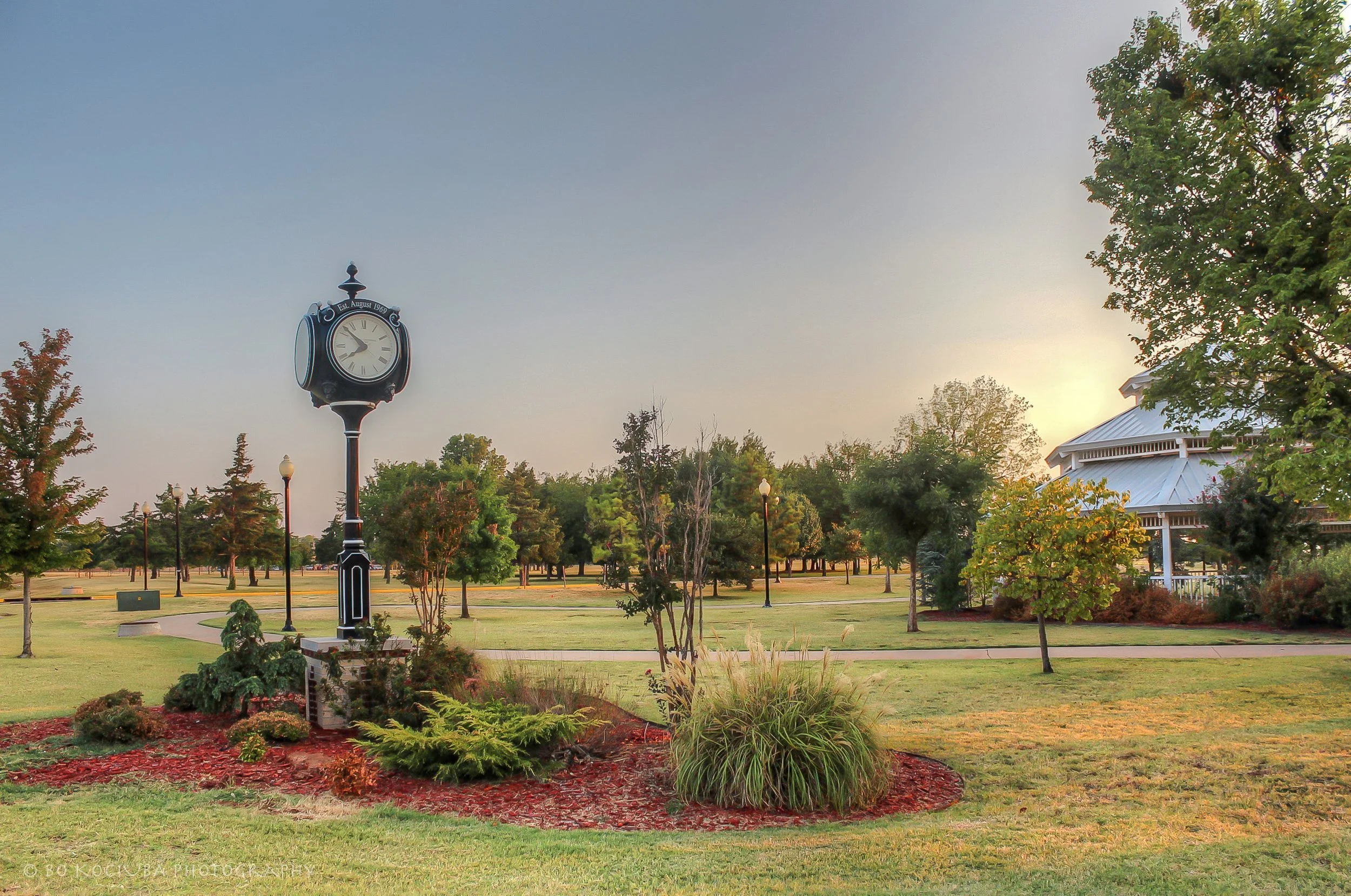 Welcome to Mustang, Oklahoma, monument along historic Route 66, featuring stonework, decorative landscaping, and traditional lanterns.