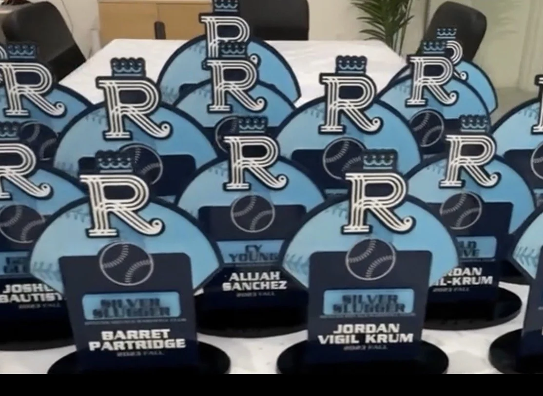 Baseball-themed awards or decorations for an event, featuring images of baseballs and large initials 'R' in a blue and black color scheme, with individual name tags for people such as Jordan Vigil Krum, Barret Partridge, and Alluah Sanchez.