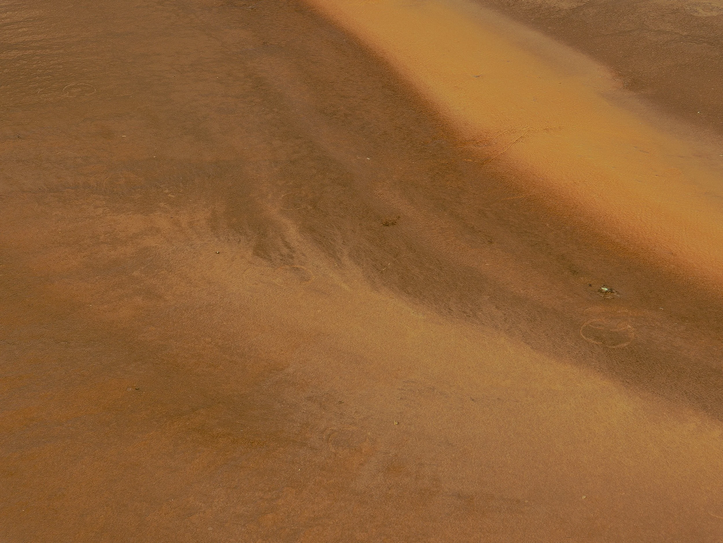 Close-up view of a sandy and textured desert landscape with a warm, golden hue.