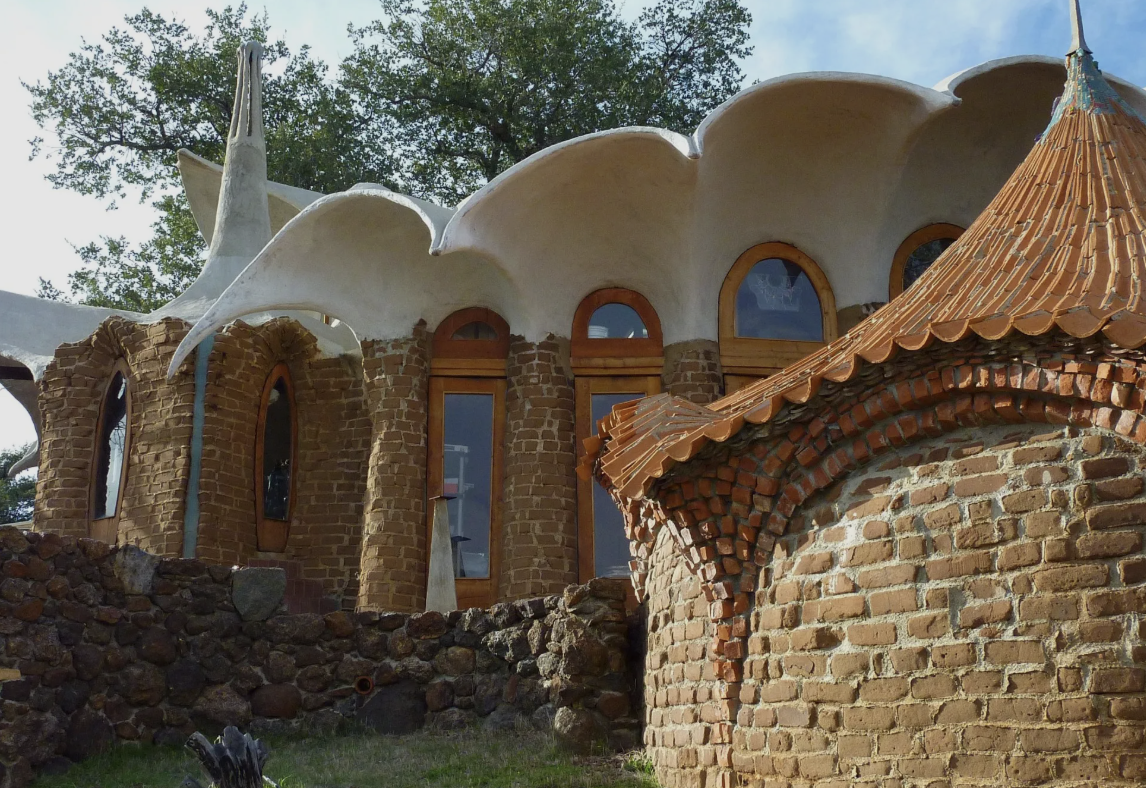 Hand-laid brick walls, a scalloped white roof, and a tiled cone-shaped roof at Ilan-Lael, the home and studio James Hubbell built by hand in Santa Ysabel, San Diego County.