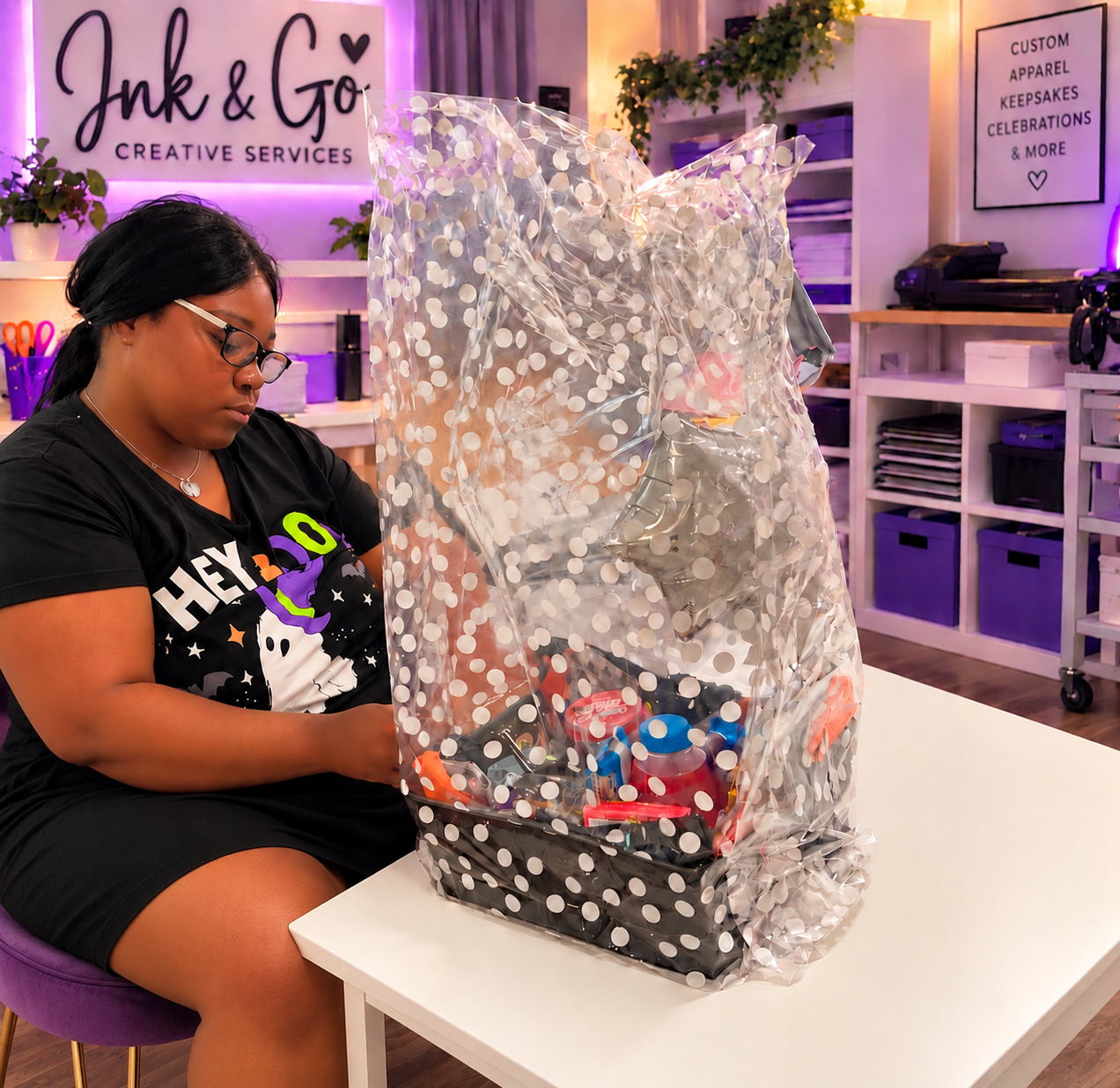 Ink & Go Creative Services owner preparing a custom gift basket in a creative workspace.