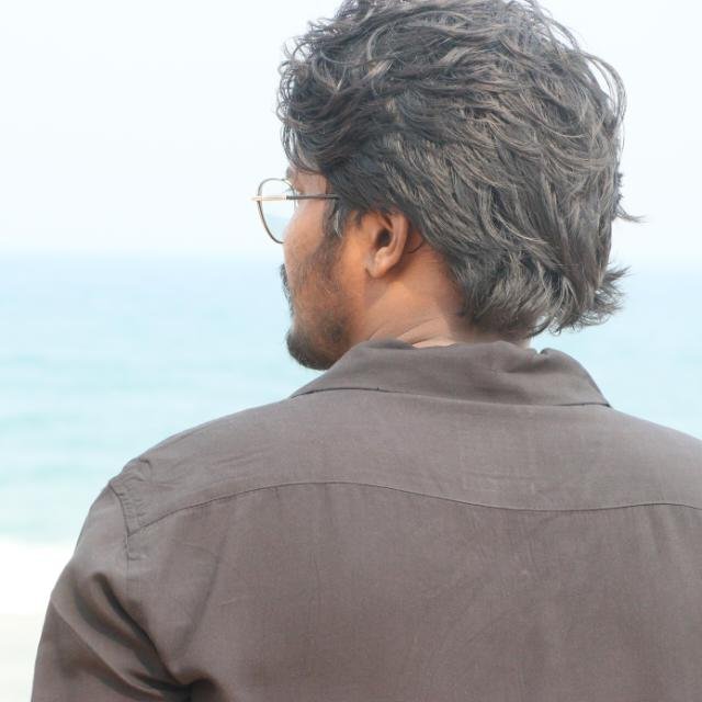 Man looking toward the ocean at the beach.