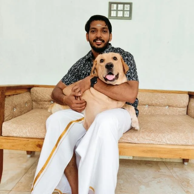 Man sitting on a couch holding a Labrador retriever.