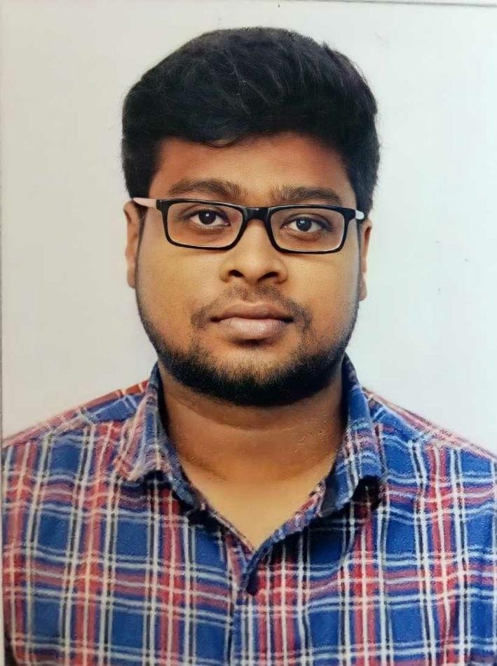 Portrait of a young man wearing glasses and a blue and red plaid shirt.